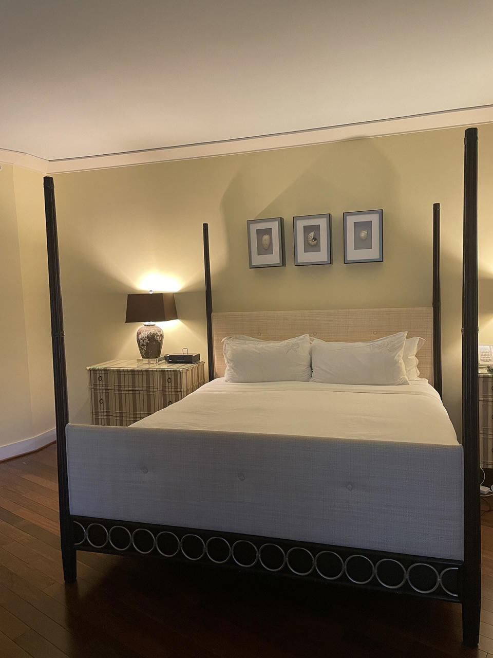 The four-poster king bed in the room I stayed in, with a striped dresser next to it and shadowbox-framed seashells over the headboard