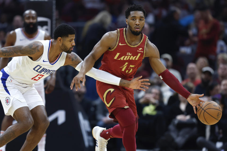 Cleveland Cavaliers guard Donovan Mitchell (45) controls the ball against Los Angeles Clippers forward Paul George (13) during the first half of an NBA basketball game, Monday, Jan. 29, 2024, in Cleveland. (AP Photo/Ron Schwane)