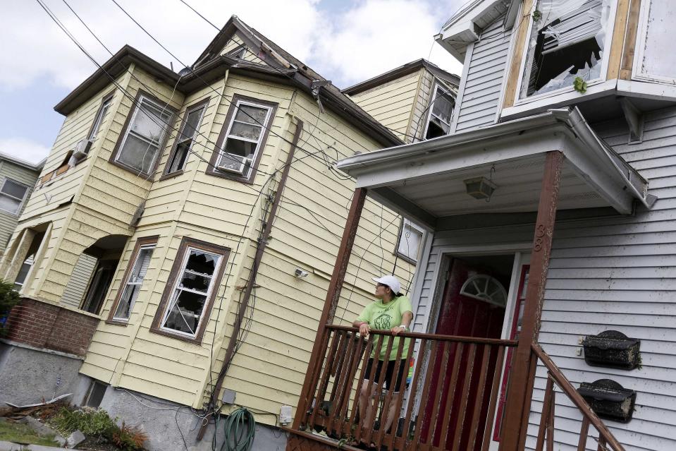 A woman looks at her neighbours' properties from her porch on Taft Street in Revere, Massachusetts, July 28, 2014. Police and emergency crews in Revere, outside Boston scrambled to clean up after a rare tornado touched down on Monday, downing power lines, damaging homes and overturning at least one car.The National Weather Service confirmed that a tornado touched down during a storm that brought heavy rains, lightning and flooding to Boston and many of its northern suburbs. State emergency management officials said they were not aware of major injuries or fatalities from the storm. (REUTERS/Dominick Reuter)