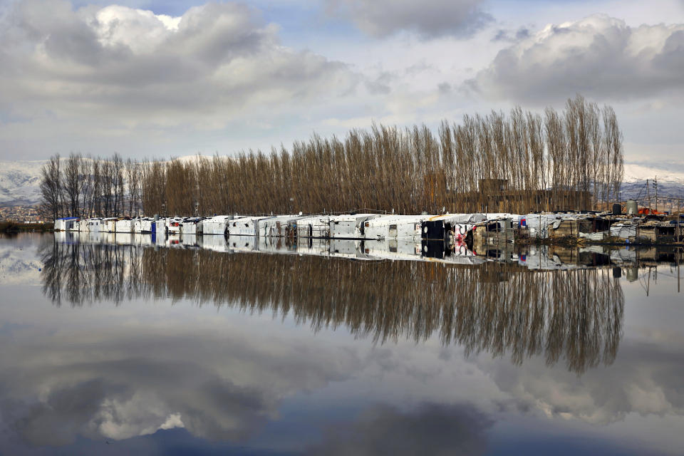 Carpas de refugiados sirios se reflejan en el agua de lluvia en un campo de refugiados en el pueblo de Bar Elias, en el valle Bekaa, en Líbano, el jueves 10 de enero de 2019. (AP Foto/Bilal Hussein)