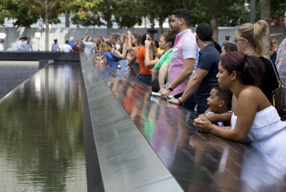 FILE- In this Sept. 9, 2015 file photo, visitors look at the waterfalls at the World Trade Center Memorial in New York. As they have done 17 times before, a crowd of victims' relatives is expected at the site on Wednesday, Sept. 11, 2019 to observe the anniversary the deadliest terror attack on American soil. (AP Photo/Mark Lennihan)