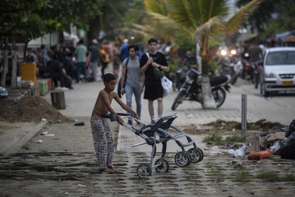 A migrant child plays with a baby car on the street, in Necocli, Colombia, Saturday, Oct. 7, 2023. New York City Mayor Eric Adams has capped off a four-day trip to Latin America with a visit to the northern Colombian city where thousands of migrants start the perilous trek across the Darien jungle, as they head to the United States. (AP Photo/Ivan Valencia)