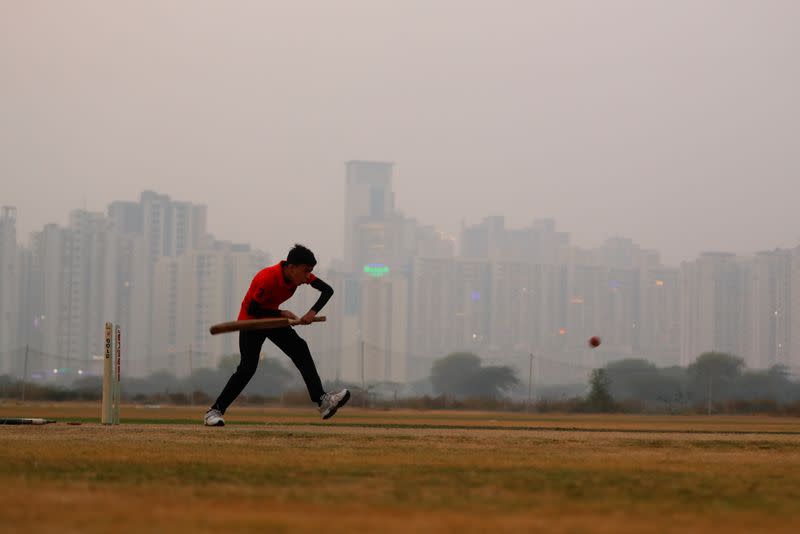 A boy plays cricket amidst smog at a playground in Noida on the outskirts of New Delhi