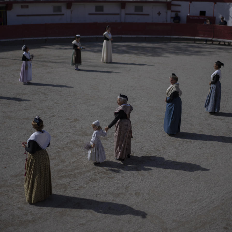 Local residents dressed in traditional Camargue clothes participate in the opening ceremony of a regional type of bull fighting in the arena of Salin de Giraud, in Camargue, southern France, Sept. 25, 2022. (AP Photo/Daniel Cole)