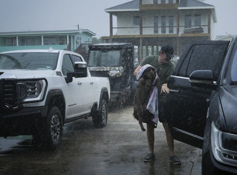 Blake Braun carga a su perra Dolly en el vehículo de su familia mientras las bandas exteriores de la tormenta tropical Beryl comienzan a golpear la costa el domingo 7 de julio de 2024, en Port O'Connor, Texas. 