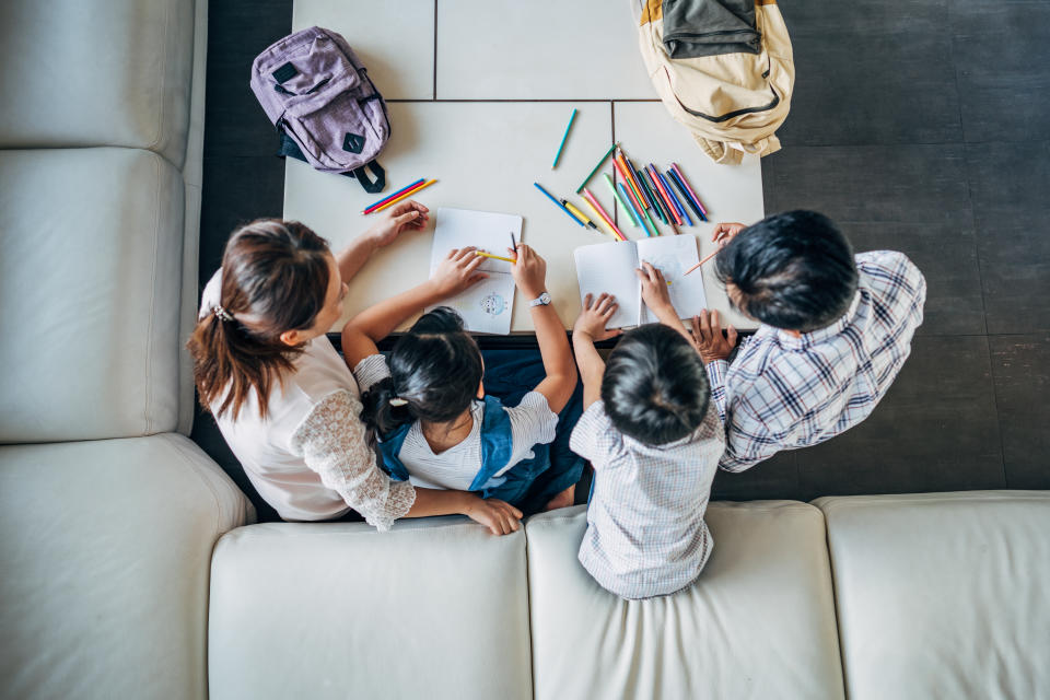 Group of people, parents doing homework with two children together at home.