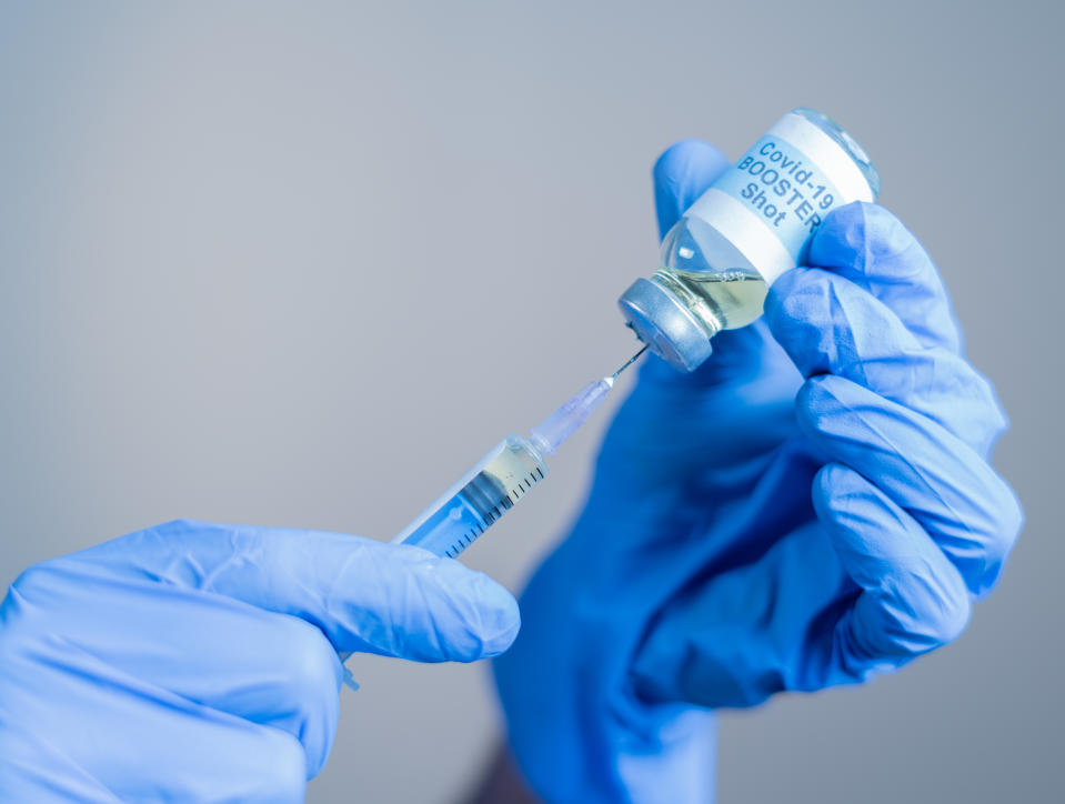 Focus on syringe, close up of doctor or nurse hands taking covid vaccination booster shot or 3rd dose from syringe.