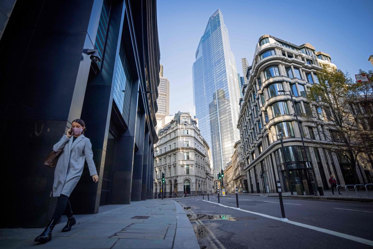 A woman wearing a protective face covering walks along a quiet street in the City of London. Photo: Tolga Akmen/AFP