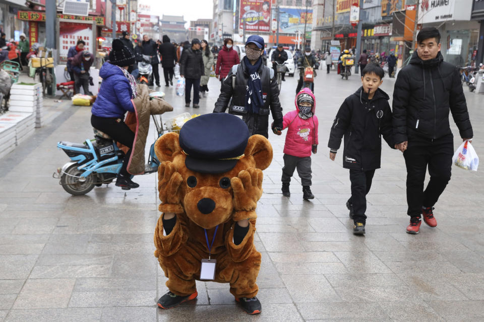 In this Saturday, Dec. 22, 2018, photo, a promoter dressed as a teddy bear rest along a retail street in Zhangjiakou in northern China's Hebei province. At least four Chinese cities and one county have restricted Christmas celebrations this year. Churches in another city have been warned to keep minors away from Christmas, and at least ten schools nationwide have curtailed Christmas on campus, The Associated Press has found. (AP Photo/Ng Han Guan)