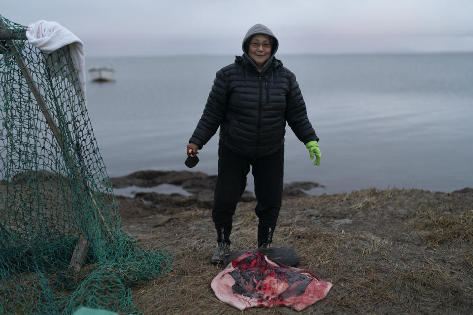 Mary Kakoona, 63, pauses for a photo while removing fat from seal skin in Shishmaref, Alaska, Tuesday, Oct. 4, 2022. “I know we gotta move sometime,” Mary said about a relocation that at times seems inevitable. “Water is rising and this island is getting smaller.” (AP Photo/Jae C. Hong)