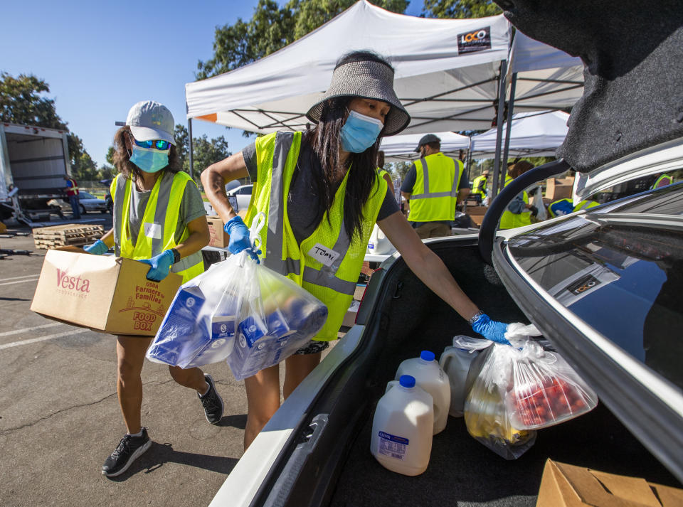 Volunteer Anh Tonnu (left) and sister Tomi Tonnu load a car in Fountain Valley, California, with food on Oct. 14 as part of Saddleback Church's drive-thru food distributions to families in need. (Photo: Allen J. Schaben/Los Angeles Times via Getty Images)