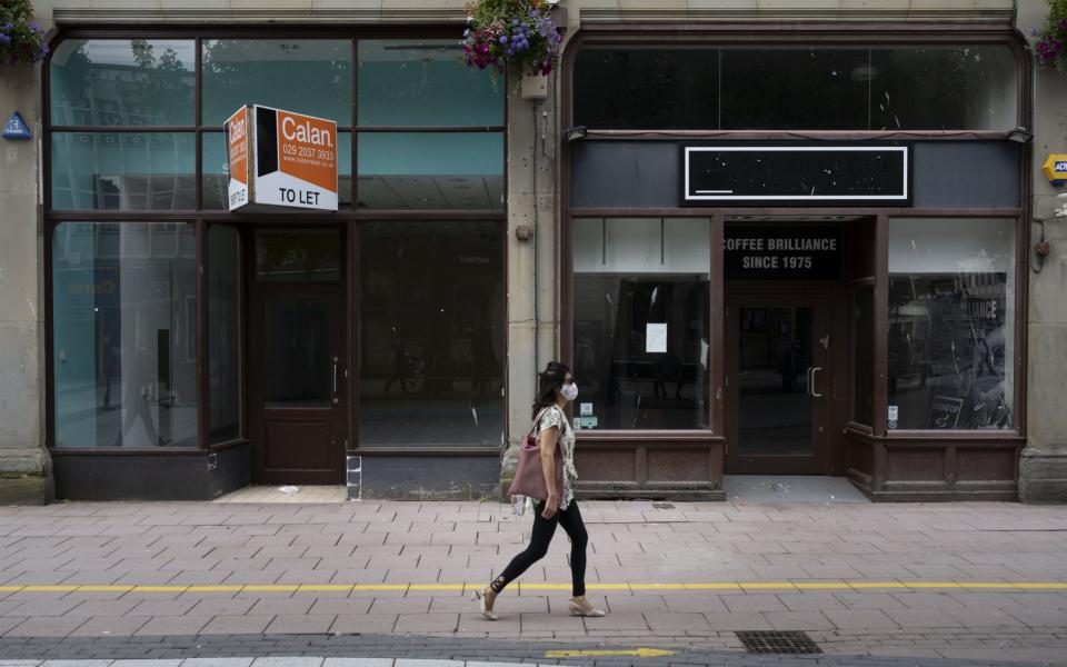 A woman wearing a surgical face mask walks passed closed shops 
