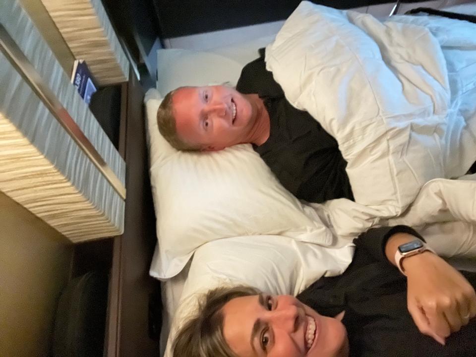 two adults laying down in a bed on a first class flight