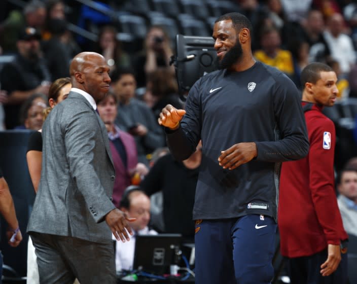 Cleveland Cavaliers forward LeBron James, right, greets television announcer and retired NBA player Chauncey Billups.