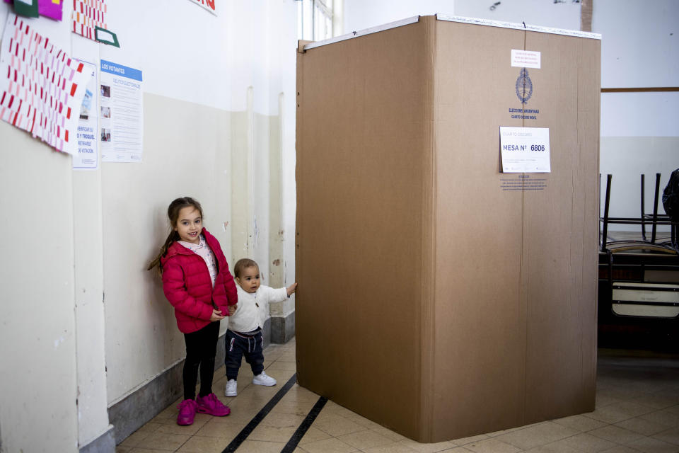 Two girls wait for their mother to cast her ballot at a polling station during primary elections in Buenos Aires, Argentina, Sunday, Aug. 11, 2019. Argentina is holding primary elections Sunday which are expected to provide a hint of who might win ahead of October's presidential elections. (AP Photo/Tomas F. Cuesta)