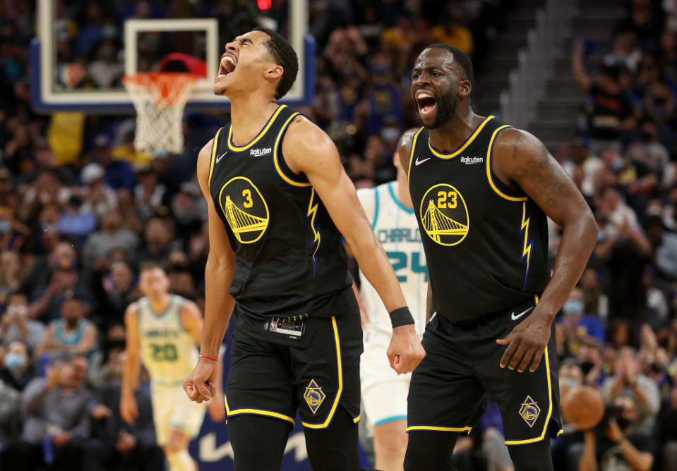 Jordan Poole #3 and Draymond Green #23 of the Golden State Warriors react after Poole made a three-point basket against the Charlotte Hornets