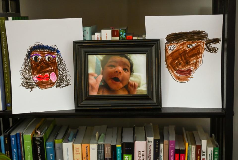 Charity Watkins’ daughter recently drew portraits of her parents, which they display with her baby photo. (Kate Medley for KFF Health News)