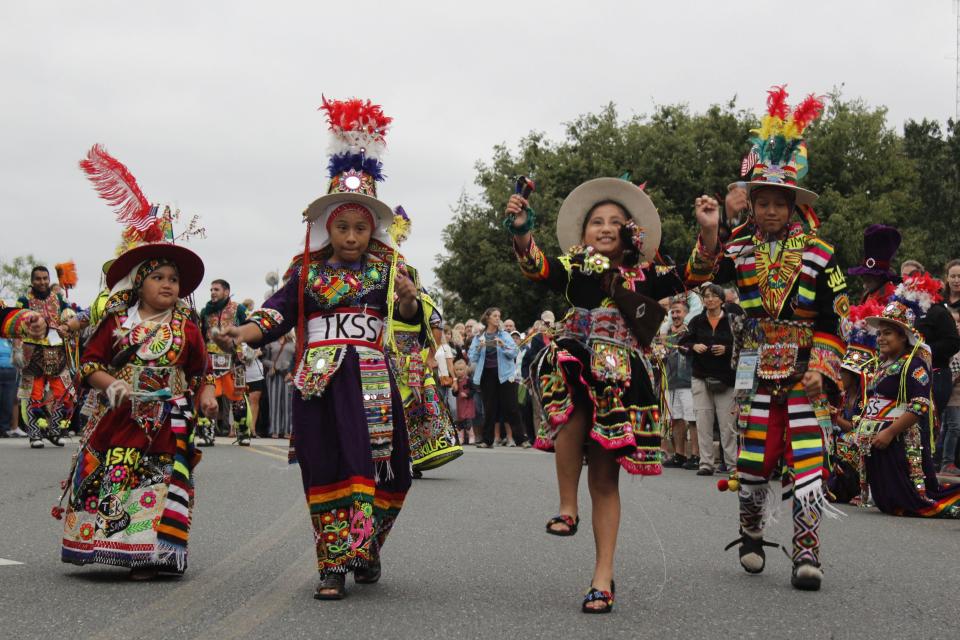 Children with Tinkus San Simon, a vibrant Bolivian dance troupe from Northern Virginia, parade down South Division Street as part of the National Folk Festival 2019.