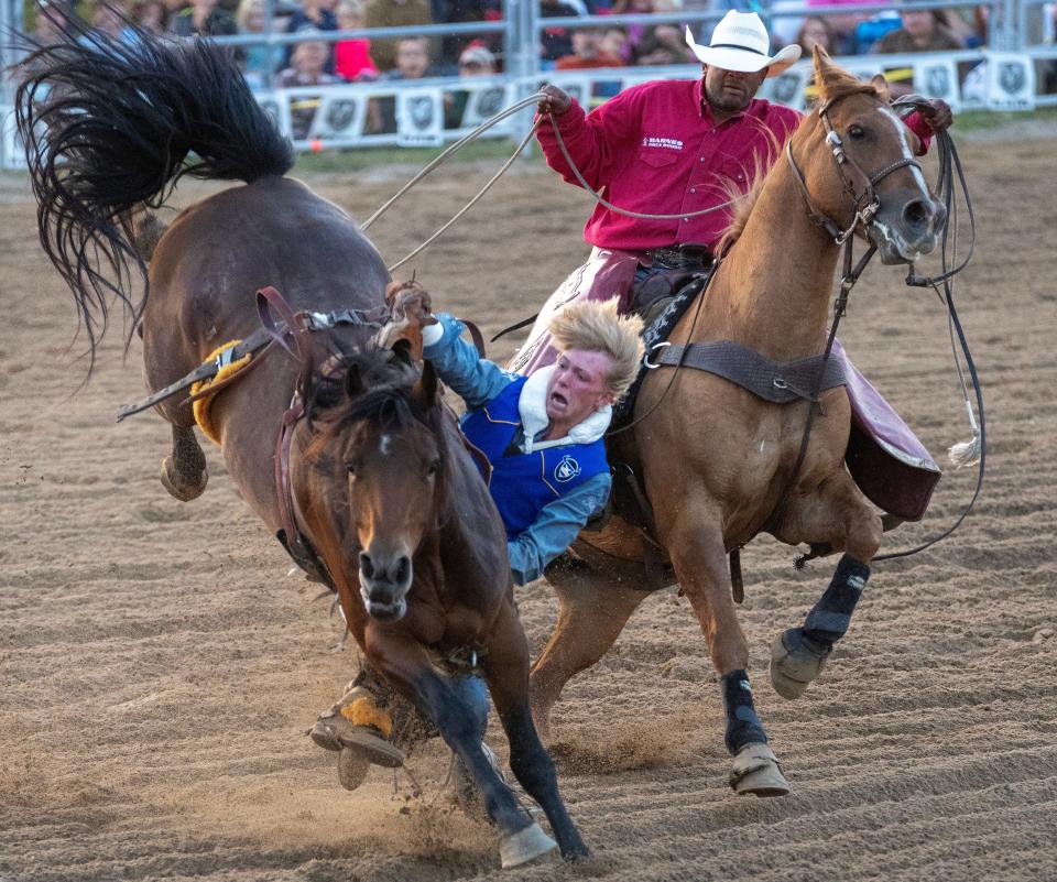 A rodeo professional tries to extricate Jackson Lunn from a dangerous situation during the 2023 UW-River Falls rodeo.