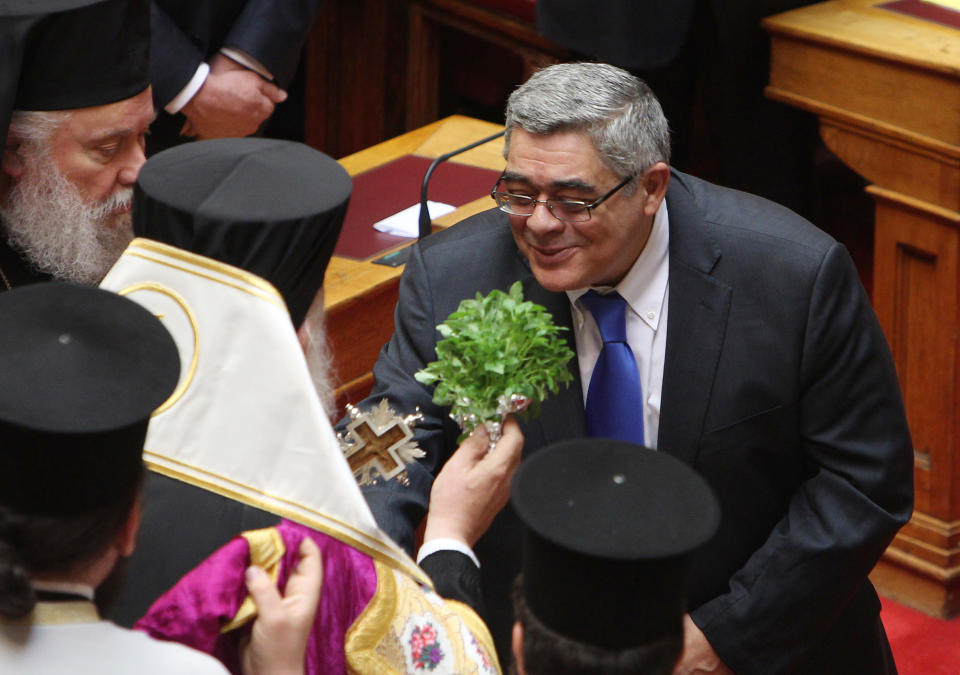 Leader of the extreme right-wing Golden Dawn party kisses the cross as Archbishop of Greece Ieronymos blesses newly sworn-in parliamentarians during a ceremony at the Greek parliament in Athens, Thursday, May 17, 2012. Among the deputies to take their seats for a day are 21 from the Golden Dawn party, which rejects the neo-Nazi label. It campaigned on pledges to rid Greece of immigrants and clean up neighborhoods. (AP Photo/Thanassis Stavrakis)