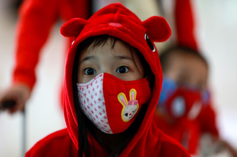 A child wears a mask to prevent the spread of the new coronavirus as they arrive at Suvarnabhumi Airport in Bangkok