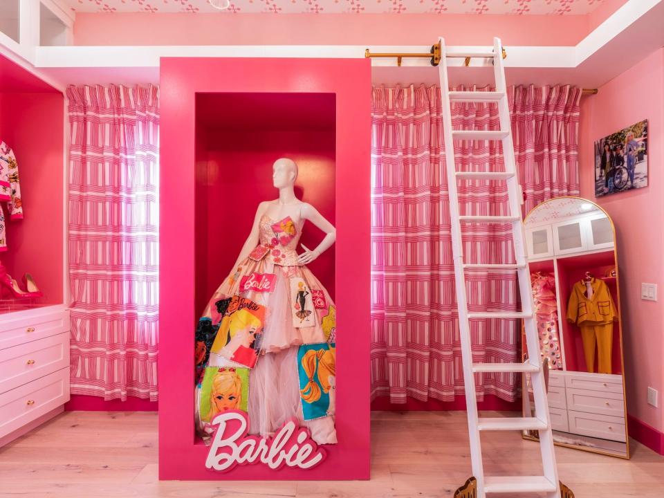 A pink, walk-in closet with a mannequin in a Barbie box.