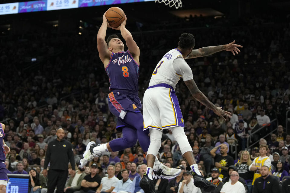 Phoenix Suns guard Grayson Allen (8) drives against Los Angeles Lakers guard D'Angelo Russell (1) during the second half of an NBA basketball game, Sunday, Feb. 25, 2024, in Phoenix. (AP Photo/Rick Scuteri)