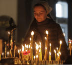 A woman lights a candle in memory of victims of shooting in the vocational college in Kerch, Crimea, in a church in St.Petersburg, Russia, Thursday, Oct. 18, 2018. An 18-year-old student strode into his vocational school in Crimea, Wednesday, then pulled out a shotgun and opened fire, killing 19 students and wounding more than 50 others before killing himself. (AP Photo/Dmitri Lovetsky)