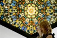 A visitor to the Hilario Galguera gallery in Mexico City takes a photo as she stands in front of a piece by Damien Hirst titled "Faithless" consisting of butterfly wings on canvas and household gloss February 23, 2006.