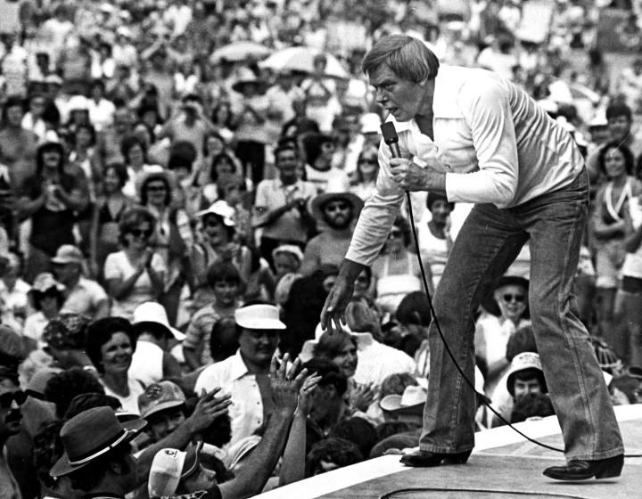 Tom T. Hall leans to the edge of the stage in 1977.