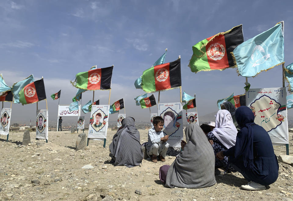 File - In this Monday, Sept 14, 2020 file photo, families gather at the graves of their relatives, adorned with their pictures, on the outskirts of Kabul, Afghanistan. Afghanistan has been at war for more than 40 years, first against the invading Soviet army that killed more than 1 million people, then feuding mujahedin groups in a bitter civil war followed by the repressive Taliban rule and finally the latest war that began after the 2001 U.S.-led coalition invasion that toppled the Taliban government. (AP Photo/Rahmat Gul, File)