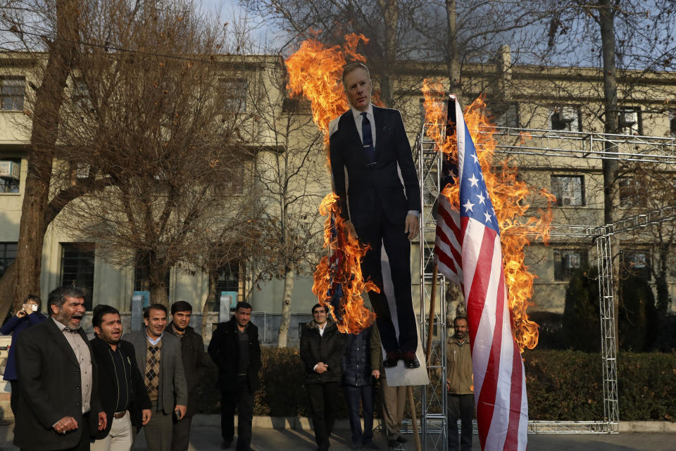 Pro-government protesters set fire to U.S. and British flags with a life size cut-out of Britain's ambassador to Tehran Rob Macaire, in a gathering to commemorate the late Iranian Gen. Qassem Soleimani, who was killed in Iraq in a U.S. drone attack on Jan. 3, and victims of last week's Ukrainian plane crash outside Tehran, at the Tehran University campus in Tehran, Iran, Tuesday, Jan. 14, 2020. (AP Photo/Vahid Salemi)