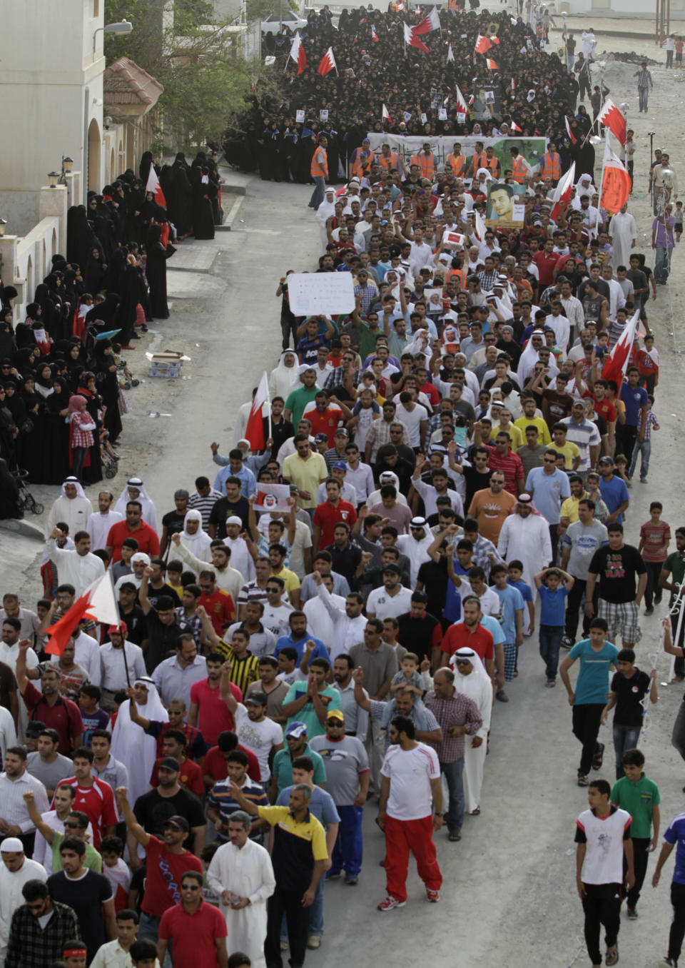 Bahraini anti-government protesters wave national flags during a march Tuesday, April 17, 2012, in Al-Dair, Bahrain, chanting anti-government slogans and carrying banners urging freedom for political prisoners. Some protesters carried signs against next Sunday's Formula One Bahrain Grand Prix, which has been the target of boycott calls. (AP Photo/Hasan Jamali)