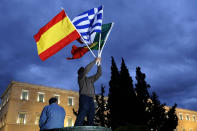 A protester holds Greek, Spanish, Irish and Portuguese flags during a demo in front of the parliament in Athens.