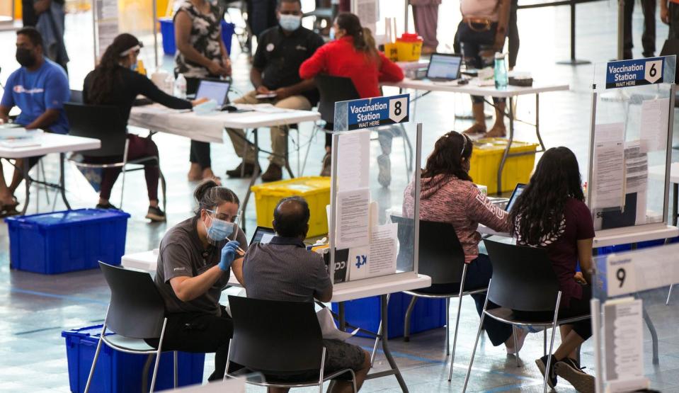 People getting vaccinated at various vaccine stations in a clinic.