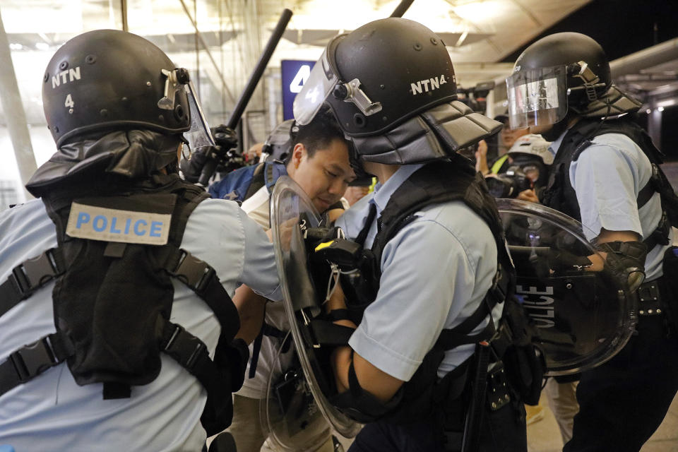 Policemen arrest a protester during a demonstration at the Airport in Hong Kong, Tuesday, Aug. 13, 2019. Riot police clashed with pro-democracy protesters at Hong Kong's airport late Tuesday night, a chaotic end to a second day of demonstrations that caused mass flight cancellations at the Chinese city's busy transport hub. (AP Photo/Vincent Yu)
