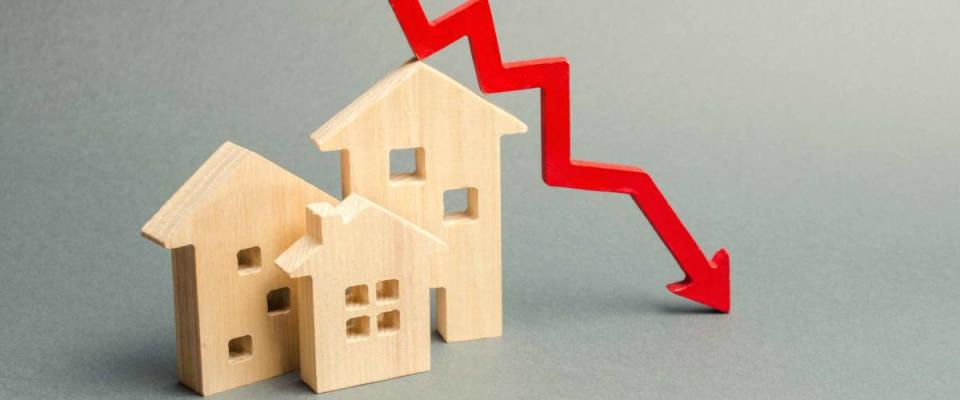 Miniature wooden houses and a red arrow down. The concept of low mortgage rates.