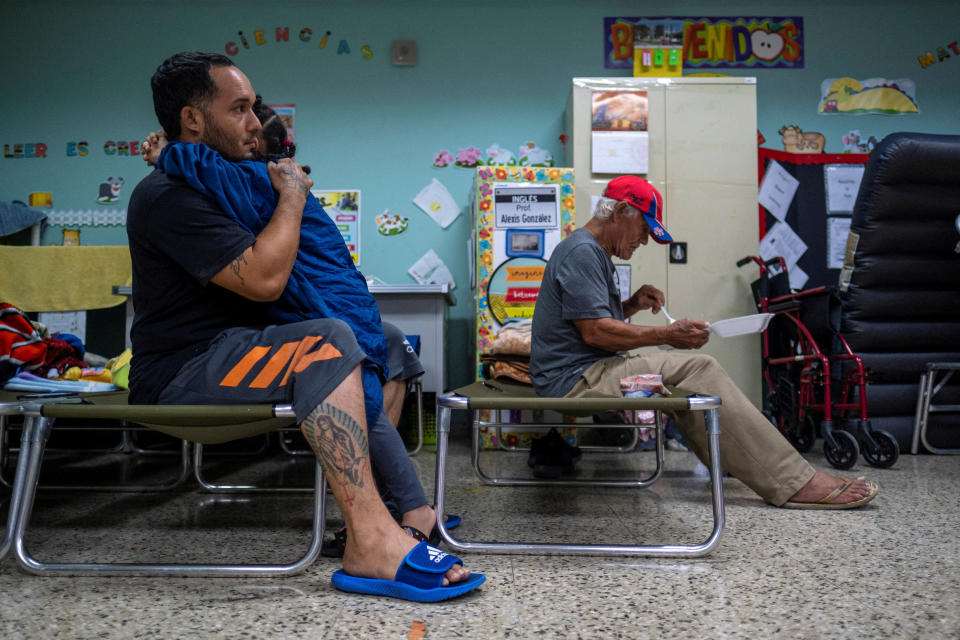 <p>A man who was evacuated from his home embraces a girl in a class room of a public school turned shelter as Hurricane Fiona and its heavy rains approaches in Guayanilla, Puerto Rico September 18, 2022. REUTERS/Ricardo Arduengo</p> 