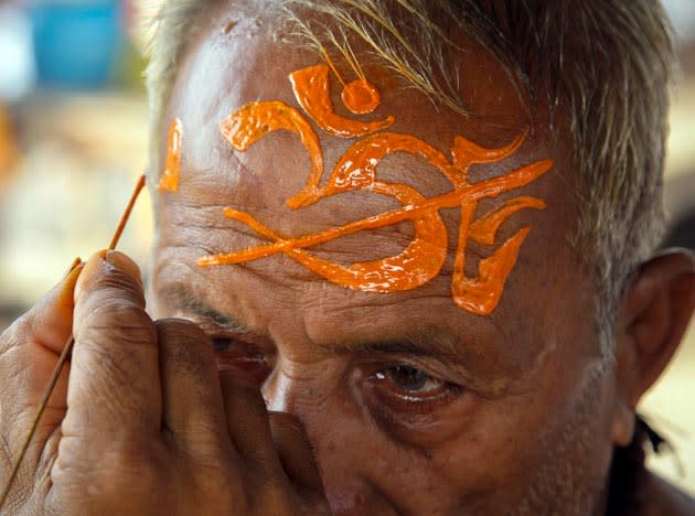 A priest paints religious symbols on the forehead of a Hindu devotee at Sangam, the confluence of the rivers Ganges, Yamuna and Saraswati during the holy month of Shravan in the northern Indian city of Allahabad, August 1, 2011. Hindu devotees fast and pray to Lord Shiva during the month of Shravan for the betterment of their family and society. REUTERS/Jitendra Prakash