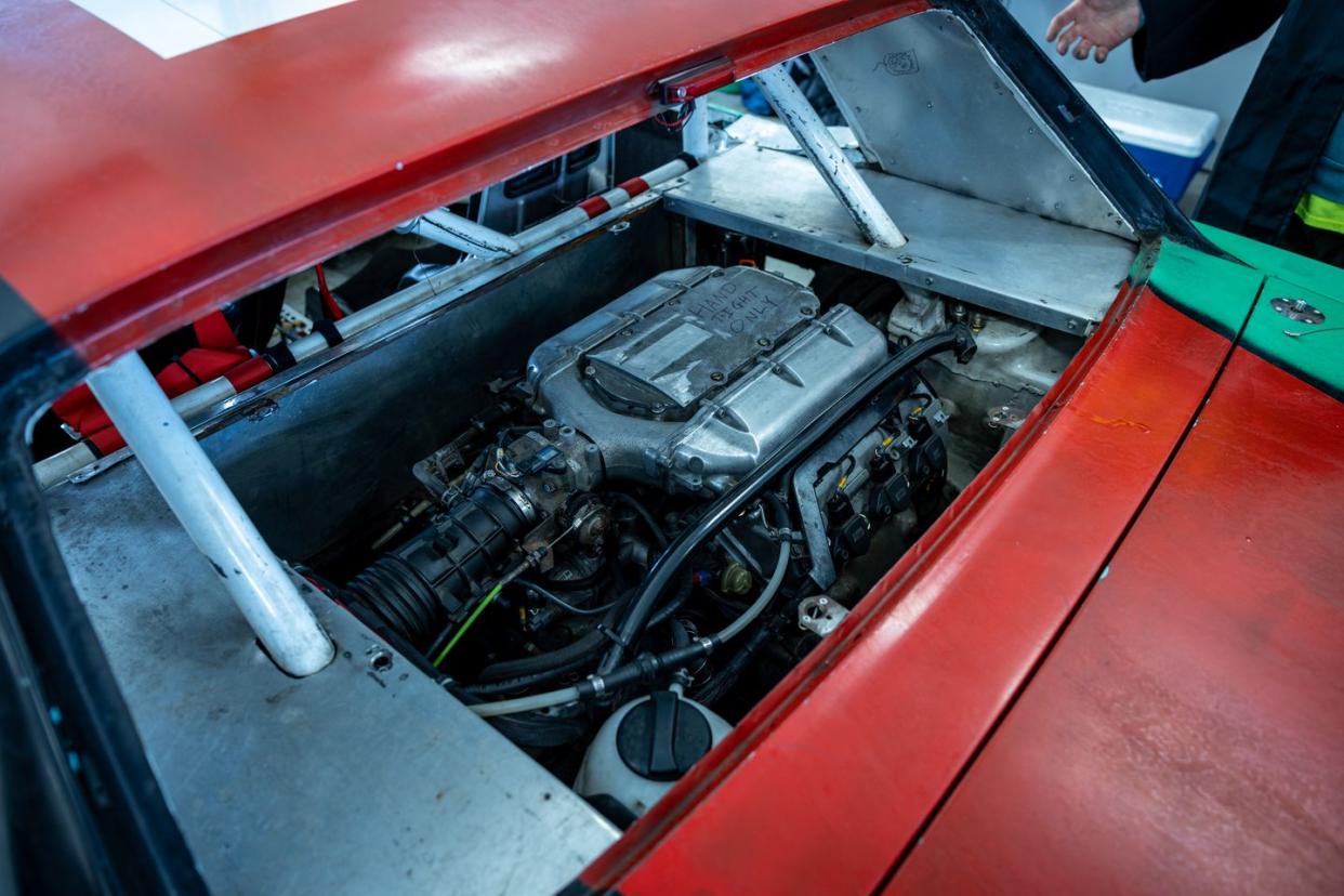 a car engine with a red car in the background