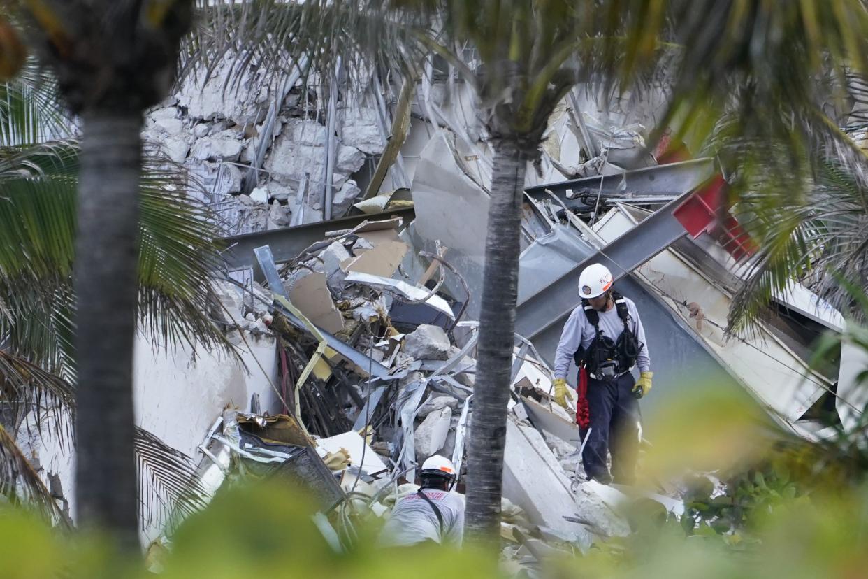 Rescue workers walk among the rubble where part of a 12-story beachfront condo building collapsed, Thursday, June 24, 2021, in Surfside, Fla.