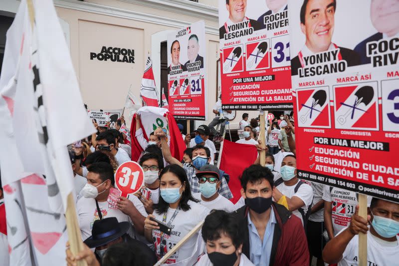 Personas agitan banderas y sostienen pancartas durante el mitin de cierre de campaña del candidato presidencial peruano Yonhy Lescano, del partido Acción Popular, en Lima, Perú