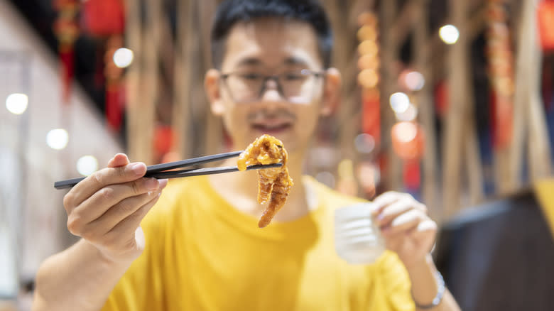 man eating fried chicken foot