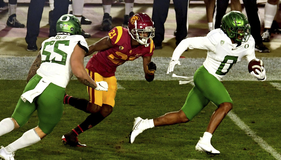 Cornerback Deommodore Lenoir, right, of Oregon, intercepts a pass intended for wide receiver Tyler Vaughns, center, of USC in the first half of an NCAA college football game at the Los Angeles Memorial Coliseum in Los Angeles on Friday, Dec. 18, 2020. (Keith Birmingham/The Orange County Register via AP)