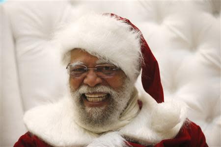 African American Santa Claus Langston Patterson, 77, laughs as he greets children at Baldwin Hills Crenshaw Plaza mall in Los Angeles, California, December 16, 2013. REUTERS/Lucy Nicholson