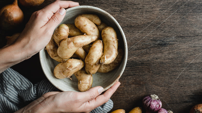 hands holding bowl of potatoes