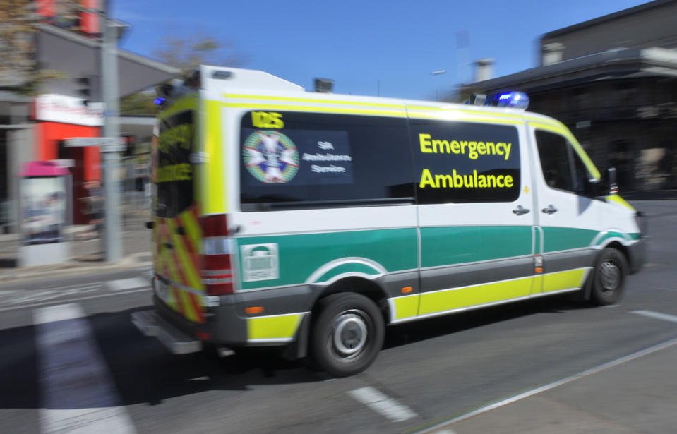 Pictured is an ambulance speeding through an intersection with flashing lights.