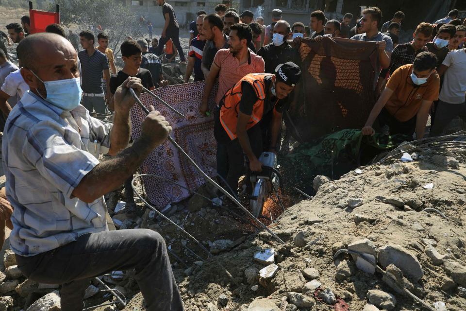 Palestinians work to clear the rubble of a collapsed building following an Israeli airstrike (AFP via Getty Images)