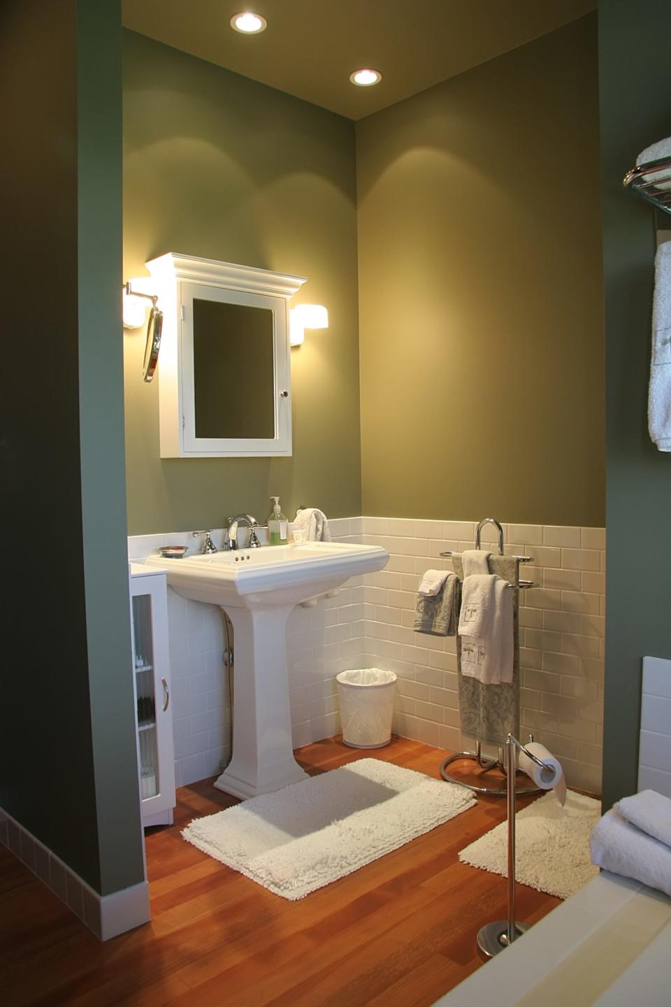 A bathroom with a sink, vanity, and multiple bath mats.
