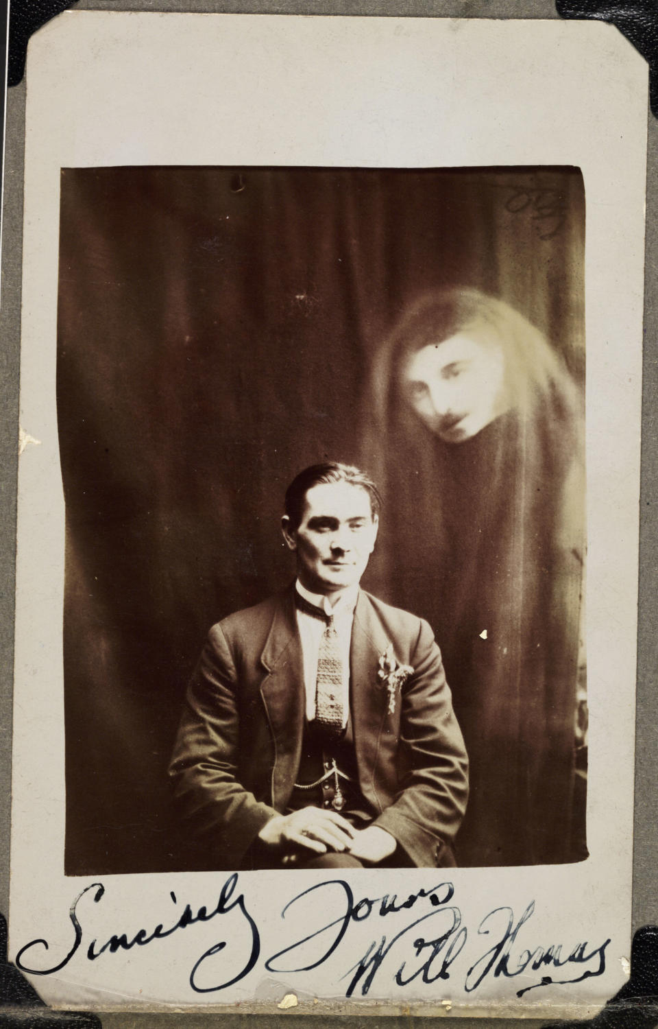 A photograph of Will Thomas, taken by William Hope (1863-1933). A man's face appears in a haze of drapery on the right of the photograph. Thomas, a medium from Wales, did not recognise the superimposed image. Thomas has signed the bottom of the photograph, 'Sincerely Yours Will Thomas' - perhaps this indicates a friendship with Hope. Hope's spirit album photographs use double and even triple exposure techniques to render the appearance of ghostly apparitions around the sitter. Hope founded the spiritualist society known as the Crewe Circle and his work was popular after World War One when many bereaved people were desperate to find evidence of loved ones living beyond the grave. Although his deception was publicly exposed in 1922, he continued to practice. (Photo by SSPL/Getty Images)